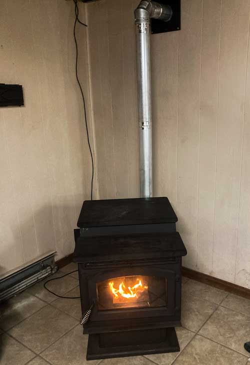 Freestanding pellet stove installation with venting to exterior wall